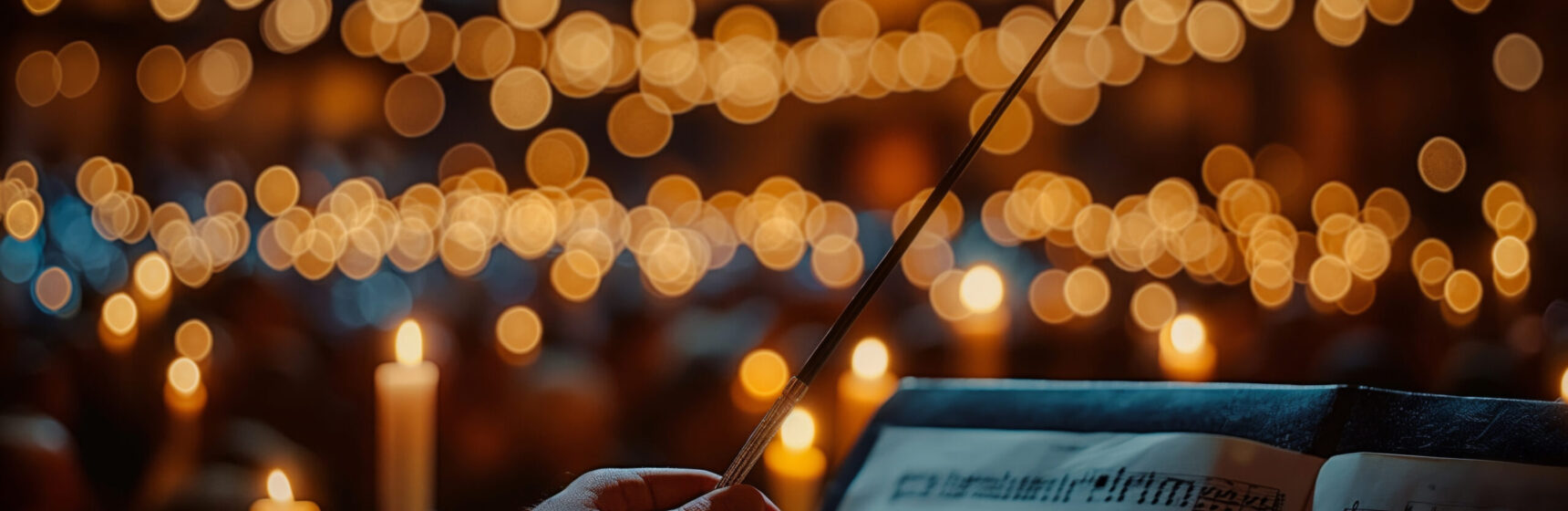 Conductor's hand holding a baton, with candlelit background and musical notes in the foreground.